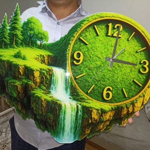 May include: A unique wall clock featuring a landscape design with a waterfall, trees, and a clock face. The clock face has a green background with yellow numerals and hands. The clock is held by a person.