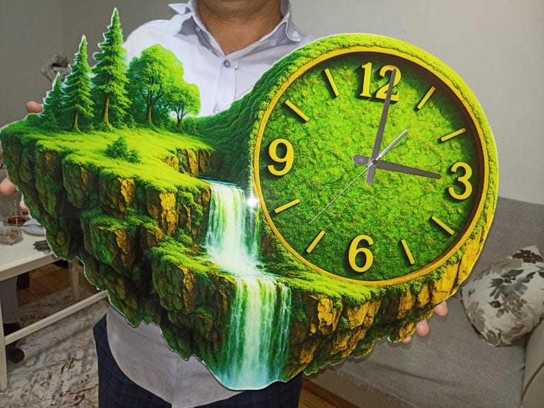 May include: A unique wall clock featuring a landscape design with a waterfall, trees, and a clock face. The clock face has a green background with yellow numerals and hands. The clock is held by a person.