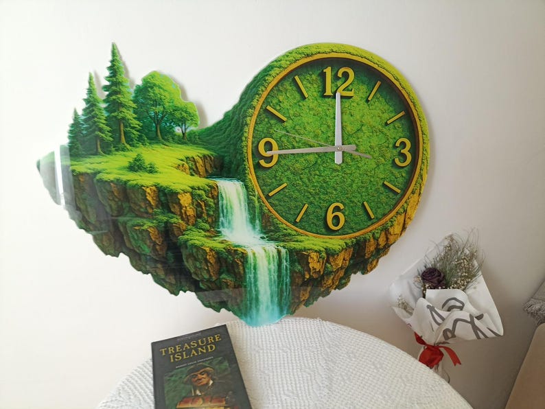 May include: A unique wall clock featuring a landscape design with a waterfall, trees, and a clock face. The clock has a green face with gold-colored numerals and hands. The clock is mounted on a white wall.