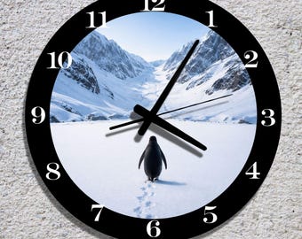 May include: Black and white wall clock with a scenic image of a penguin walking in the snow with a mountain backdrop. The clock face has black numbers and hands, and a black border.