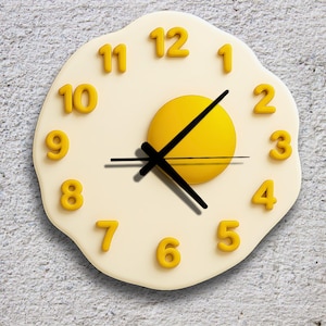 Può includere: Un orologio da parete stravagante a forma di uovo fritto. L'orologio presenta un tuorlo giallo, un uovo bianco e numeri gialli. Le lancette nere indicano l'ora. Un pezzo decorativo e divertente per una cucina o una sala da pranzo.