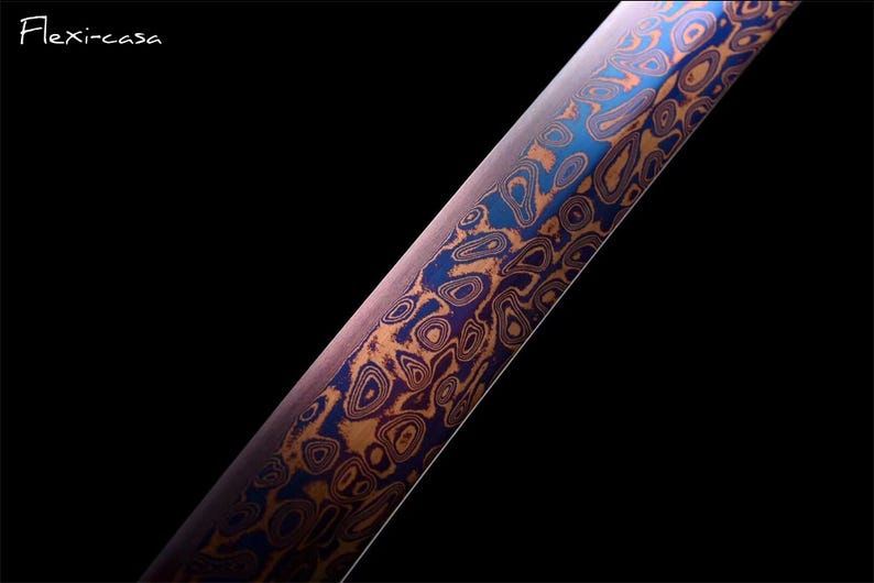 May include: Close-up of a blade with a unique pattern. The blade features a swirling design in shades of blue, orange, and purple against a dark background. The text "Flexi-casa" is in the upper left corner.