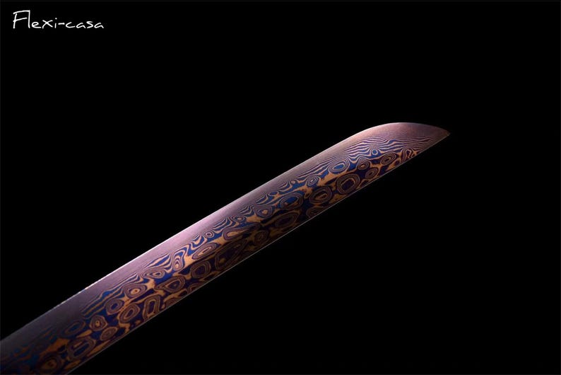 May include: Close-up of a blade with a unique pattern of swirling blue and gold designs on a purple background. The blade has a curved edge and is set against a black backdrop. The text "Flexi-casa" is in the upper left corner.