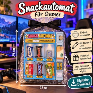 Pode incluir: Uma caixa de presente em forma de máquina de venda automática de 29 cm por 23 cm, com ranhuras para barras como Milky Way, Mars e Snickers. A frente exibe 'SNACK AUTOMAT', 'LEVEL 12 FREIGESCHALTET' e 'EIGENTUM VON DAVID'. Inclui um laço preto.