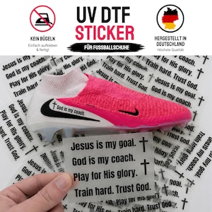 Könnte beinhalten: Ein UV-DTF-Aufkleberbogen mit dem Text 'Jesus is my goal. God is my coach. Play for His glory. Train hard. Trust God.' und Kreuzsymbolen. Die Aufkleber sind für die Anwendung auf einem weiß-pinken Fußballschuh im Hintergrund vorgesehen.
