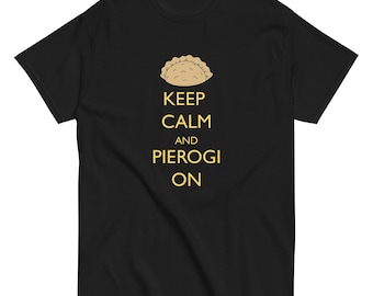 以下が含まれることがあります： 黒いTシャツ。ピエロギのグラフィックと、金色の文字で「KEEP CALM AND PIEROGI ON」と書かれています。ピエロギは薄茶色です。Tシャツはクルーネックで半袖です。