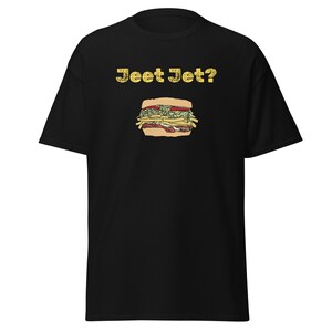 May include: Black t-shirt with a graphic of a sandwich and the text "Jeet Jet?" in yellow. The sandwich illustration includes lettuce, tomatoes, and french fries.