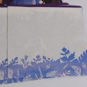 Pode incluir: Guardanapos de papel brancos com um desenho floral azul na borda inferior. Os guardanapos t&ecirc;m uma borda roxa. O desenho apresenta v&aacute;rias formas de folhas e plantas em tons de azul. Os guardanapos est&atilde;o empilhados.