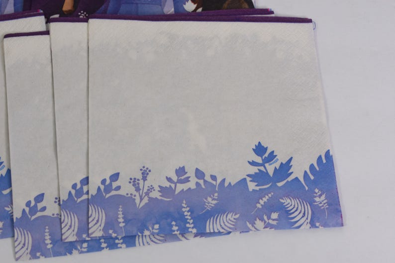 Pode incluir: Guardanapos de papel brancos com um desenho floral azul na borda inferior. Os guardanapos t&ecirc;m uma borda roxa. O desenho apresenta v&aacute;rias formas de folhas e plantas em tons de azul. Os guardanapos est&atilde;o empilhados.