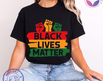 May include: Black t-shirt with the text "BLACK LIVES MATTER" in red, yellow, and green, with three raised fists above the text. The shirt is black.