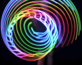 May include: A vibrant, multi-colored LED light hoop, radiating concentric circles of neon light. The hoop's colors include shades of blue, green, yellow, orange, and pink, creating a dynamic visual effect against a dark background. The light trails suggest movement.