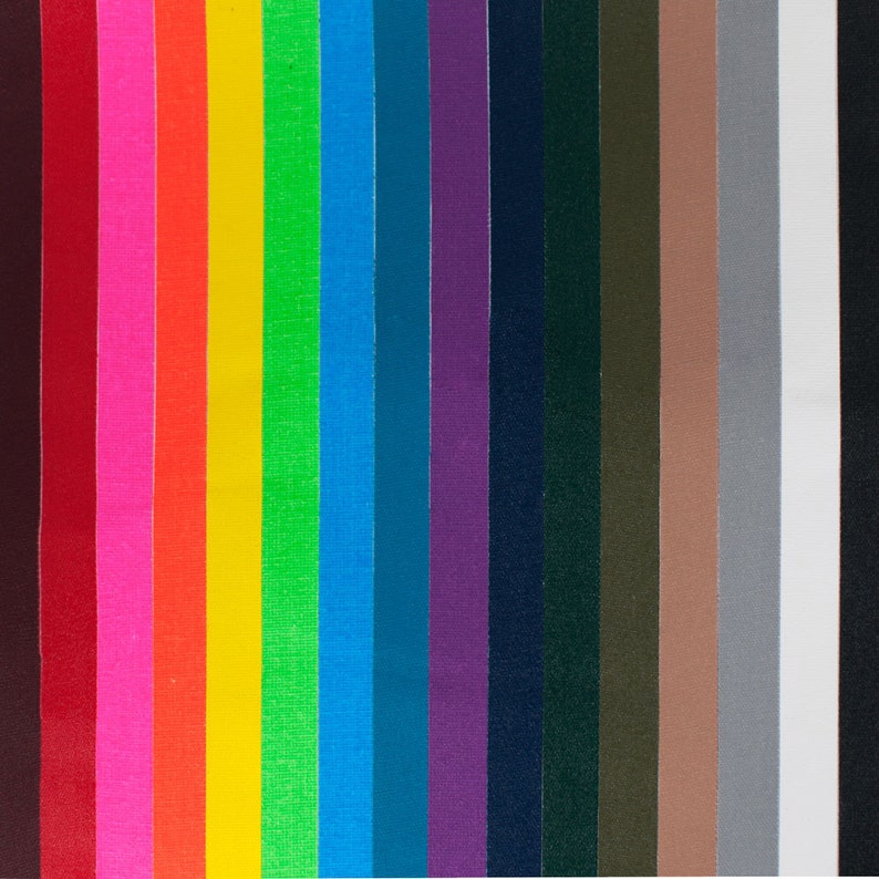 Op de afbeelding: Een verzameling stofstalen in verschillende kleuren, waaronder rood, roze, oranje, geel, groen, blauw, paars, zwart, bruin, grijs en wit.