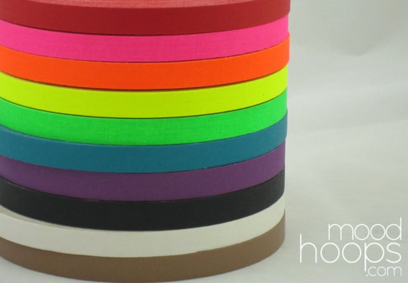 Pu&ograve; includere: Un rotolo di nastro di tessuto colorato in vari colori, tra cui rosso, rosa, arancione, giallo, verde, verde acqua, viola, nero, bianco e marrone. I rotoli sono impilati uno sopra l'altro, con il rotolo rosso in cima e il rotolo marrone in fondo. Il testo "mood hoops.com" &egrave; visibile nell'angolo in basso a destra dell'immagine.