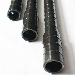 May include: Close-up of three black plastic tubes of varying lengths. The tubes have a ridged, spiral design and open ends, revealing a hollow interior. The tubes are set against a white background.