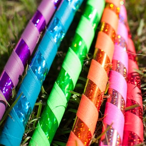 Op de afbeelding: Vijf kleurrijke hoepels met een glinsterend, gestreept ontwerp. De hoepels zijn gemaakt van plastic en zijn in een rij gerangschikt. De kleuren van de hoepels zijn paars, blauw, groen, oranje en roze.