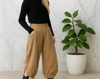 Puede incluir: Un suéter negro de cuello alto y manga larga con textura acanalada combinado con pantalones color canela de pierna ancha, bolsillos laterales, detalle de botón en el dobladillo y corte holgado. Botines negros con cordones.
