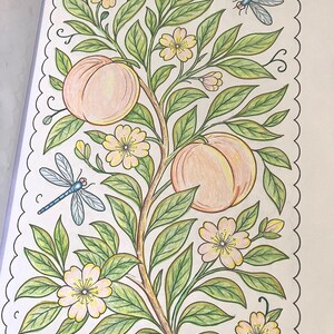 May include: A detailed coloring page featuring a peach tree with two large peaches, green leaves, and delicate yellow flowers. Two blue dragonflies are also included in the design. The image is framed with a scalloped border.