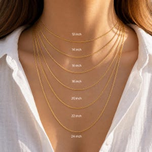 May include: A collection of seven gold-toned metal chains layered in increasing lengths. The chains are labeled with text indicating lengths of 12 inch, 14 inch, 16 inch, 18 inch, 20 inch, 22 inch, and 24 inch to demonstrate the fit of each necklace.