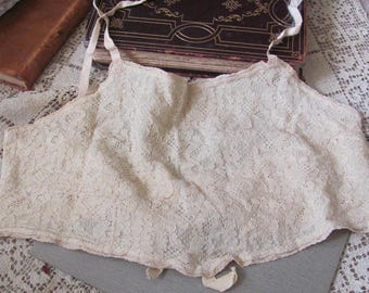 Puede incluir: Una blusa de encaje blanco delicado con un borde festoneado. La blusa tiene un diseño sencillo y es perfecta para superponer.