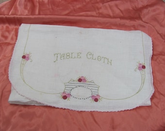 May include: White linen tablecloth with embroidered pink roses and green leaves. The text "TABLE CLOTH" is embroidered in green thread.