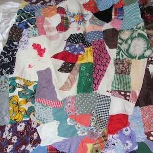 May include: A handmade patchwork quilt with a variety of fabric patterns and colors. The quilt features floral, polka dot, plaid, and solid fabrics in shades of blue, red, pink, green, and brown. The quilt is a mix of vintage and modern fabrics.