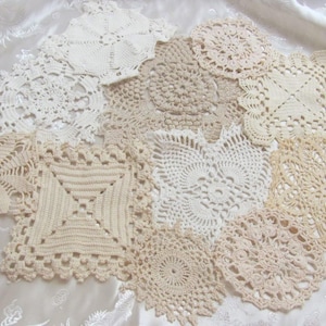 May include: A collection of ten assorted crochet doilies in various shades of white, cream, and beige. Each piece features a unique geometric or floral pattern with intricate openwork stitching, varying in circular and square shapes.