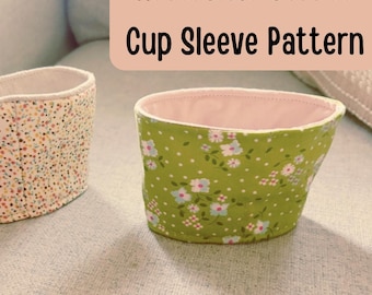 May include: Two reversible coffee cup sleeves featuring floral patterns. One sleeve has a green background with white and pink flowers, while the other has a cream background with tiny multicolored flowers. Text reads: Reversible Coffee Cup Sleeve Pattern.