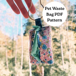 Puede incluir: Una bolsa para residuos de mascotas con estampado floral en azul y rosa, sujeta a un lazo metálico dorado. La bolsa es de tela y tiene un cierre de cinta verde. El texto en la imagen dice "Pet Waste Bag PDF Pattern."