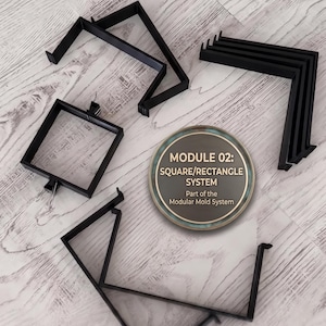 Può includere: Un set di componenti modulari neri per stampi, progettati per creare forme quadrate e rettangolari. La collezione include varie staffe angolari e una cornice quadrata, con un'etichetta circolare: MODULE 02: SQUARE/RECTANGLE SYSTEM.
