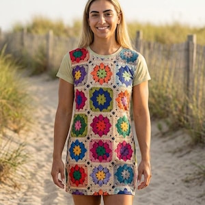 Op de afbeelding: Een vrouw draagt een kleurrijke gehaakte jurk met een bloemenpatroon. De jurk heeft een beige basis met levendige vierkanten in rood, oranje, blauw, groen en roze. De jurk wordt gecombineerd met een lichtgroen t-shirt.