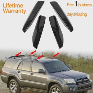 May include: Four black roof rack accessories are displayed above a gray SUV. The accessories are angled and appear to be made of a glossy material. The text "Lifetime Warranty" and "Free 1 business day shipping" are also visible.