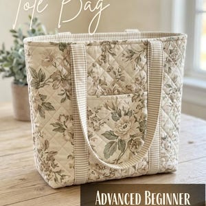 Könnte beinhalten: Eine gesteppte Tragetasche mit beigem und cremefarbenem Blumenmuster und Rautensteppung. Die Tasche verfügt über zwei gestreifte Stoffgriffe und eine Vordertasche. Der Text auf dem Bild lautet: Tote Bag und Advanced Beginner Sewing Pattern.