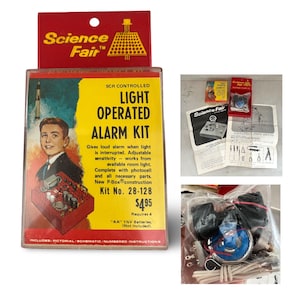 May include: Vintage Science Fair Light Operated Alarm Kit, Kit No. 28-128, with a retro design. The box features a young man, a rocket, and the text "SCR CONTROLLED LIGHT OPERATED ALARM KIT". Includes pictorial instructions and requires 4 AA batteries.