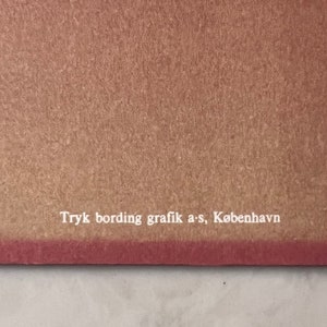 May include: Close-up of a brown paper background with white text that reads "Tryk bording grafik a-s, K&oslash;benhavn".