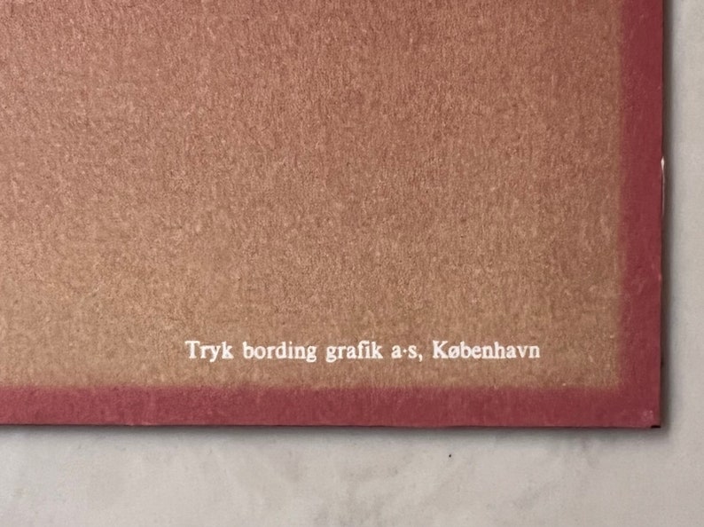 May include: Close-up of a brown paper background with white text that reads "Tryk bording grafik a-s, K&oslash;benhavn".