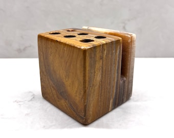 May include: A brown and white marble pen holder with eight holes for pens. The holder is made of natural stone and has a unique, organic look.