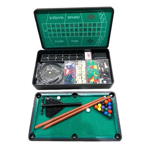 May include: A multi-game set featuring a black carrying case with a green roulette layout on the interior lid. The case contains compartments with game pieces, including dominoes, chips, and chess pieces. A miniature pool table is also included.