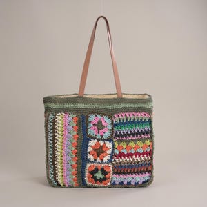 May include: A rectangular crochet tote bag featuring a dark olive green base with a multi-coloured patchwork design. The bag includes three square granny motifs and vertical striped patterns in pink, orange, blue, and yellow, with two tan leather straps.