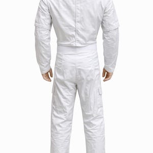 May include: A white jumpsuit with a high collar, long sleeves, and cargo pockets. The back view shows the full-body garment, including the matching pants and a white belt. The outfit is made of a smooth, possibly synthetic material.