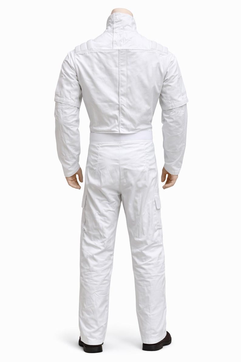 May include: A white jumpsuit with a high collar, long sleeves, and cargo pockets. The back view shows the full-body garment, including the matching pants and a white belt. The outfit is made of a smooth, possibly synthetic material.