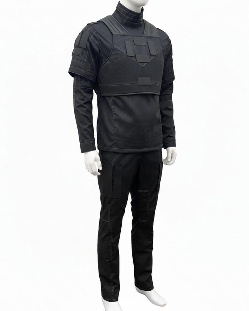 May include: A black tactical outfit displayed on a mannequin. The outfit includes a high-neck shirt, a vest with multiple panels, and cargo pants. The vest has shoulder pads and a horizontal strap across the chest. The pants have multiple pockets.
