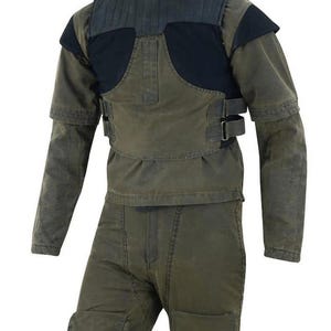 May include: A two-piece olive green and black protective suit. The jacket has a padded black chest and shoulder area, with olive green sleeves and a high collar. The pants are olive green with reinforced knee pads and a front zipper.