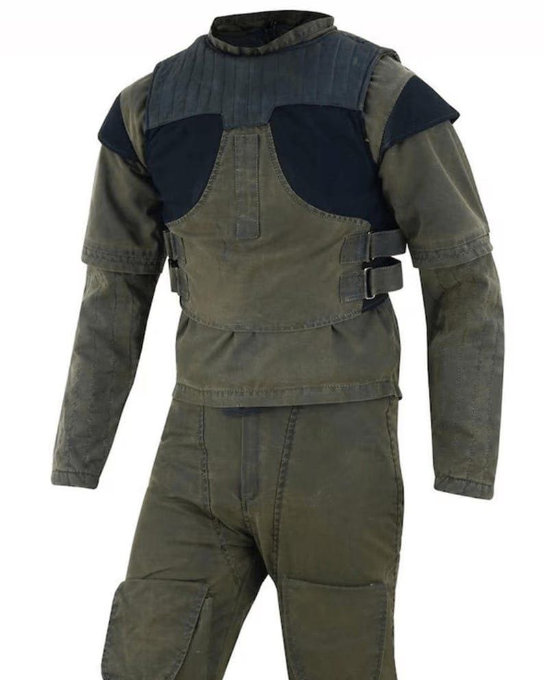 May include: A two-piece olive green and black protective suit. The jacket has a padded black chest and shoulder area, with olive green sleeves and a high collar. The pants are olive green with reinforced knee pads and a front zipper.