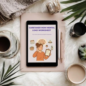 May include: A digital tablet displays a worksheet titled "Caretaker Mom Mental Load Worksheet" with illustrations. The tablet is on a light pink surface, surrounded by a cup of coffee, a pen, and decorative items, all set against a fluffy white background.