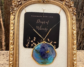 Nyckfullt blått lila halsband med torkade blommor i harts | Virvelhänge i målat glas
