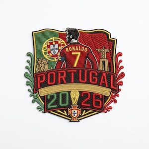Peut inclure: Un écusson brodé représentant un joueur de football en maillot rouge avec le nom RONALDO et le numéro 7. Le motif inclut le drapeau portugais, le texte PORTUGAL 2026, une icône de trophée, la statue du Christ-Roi et une silhouette de château.