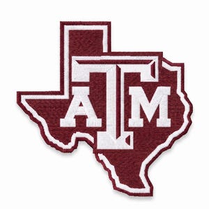 May include: A maroon and white embroidered patch in the shape of the state of Texas. The design features the white letters A and M centered within the state outline, with a large white T overlapping both letters, creating the Texas A&M university logo.