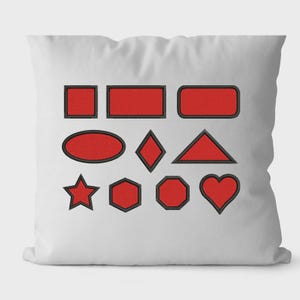 May include: White pillow with various red geometric shapes embroidered with black outlines. Shapes include squares, rectangles, an oval, a diamond, a triangle, a star, a hexagon, an octagon, and a heart.
