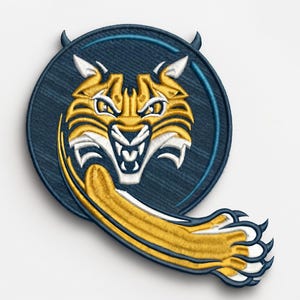 May include: A circular embroidered patch featuring a stylized bobcat head in gold and white thread against a dark blue textured background. A gold and white bobcat paw extends from the bottom right of the circle, which has two small horns.