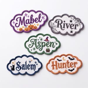 May include: Five cloud-shaped embroidered patches featuring names Mabel, River, Aspen, Salem, and Hunter. Each patch has a unique theme: pumpkins, spiderwebs, a witch hat and cauldron, a black cat, and bats with a crescent moon.